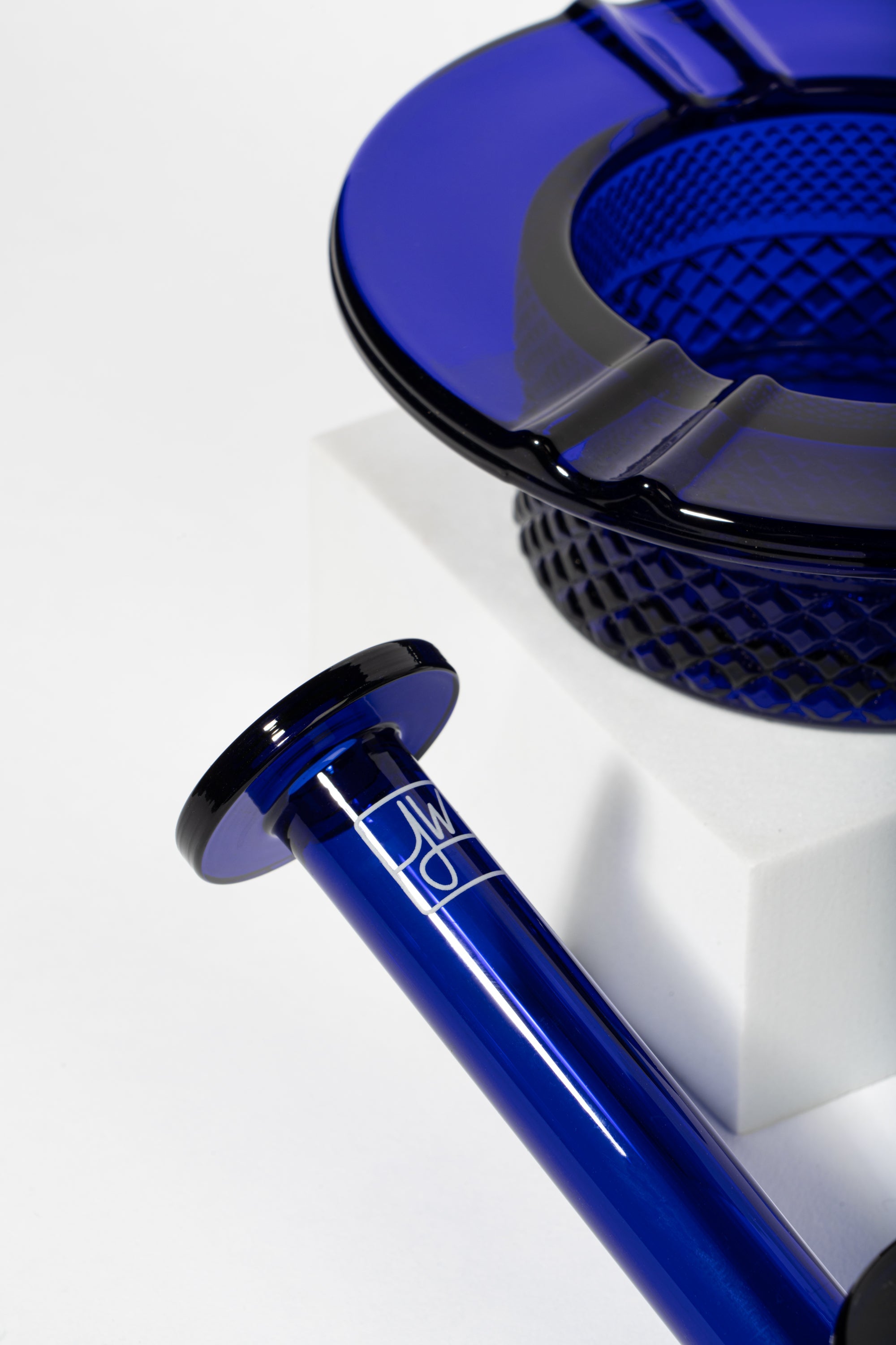 Blue glass cannabis pipe and ashtray with geometric pattern.