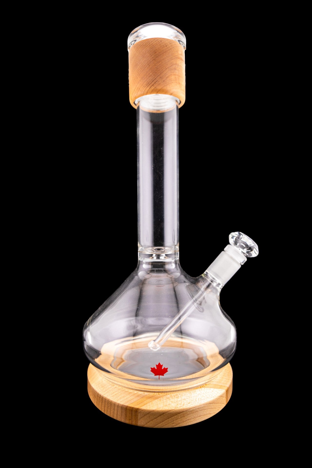 Glass water pipe with a wooden base and a Canadian maple leaf design, isolated on a black background.