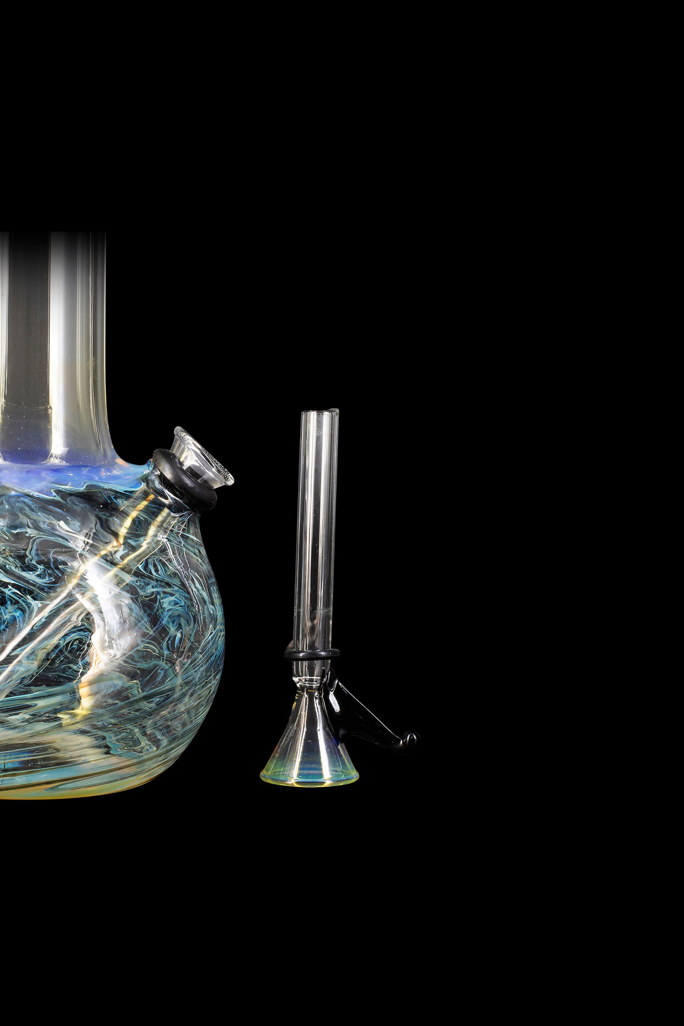 A vibrant glass water pipe and accompanying downstem against a black background.