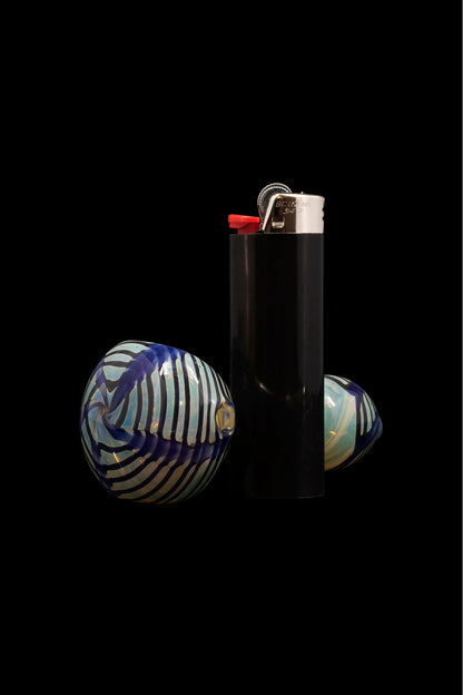 Glass marbles and a black lighter against a dark background.