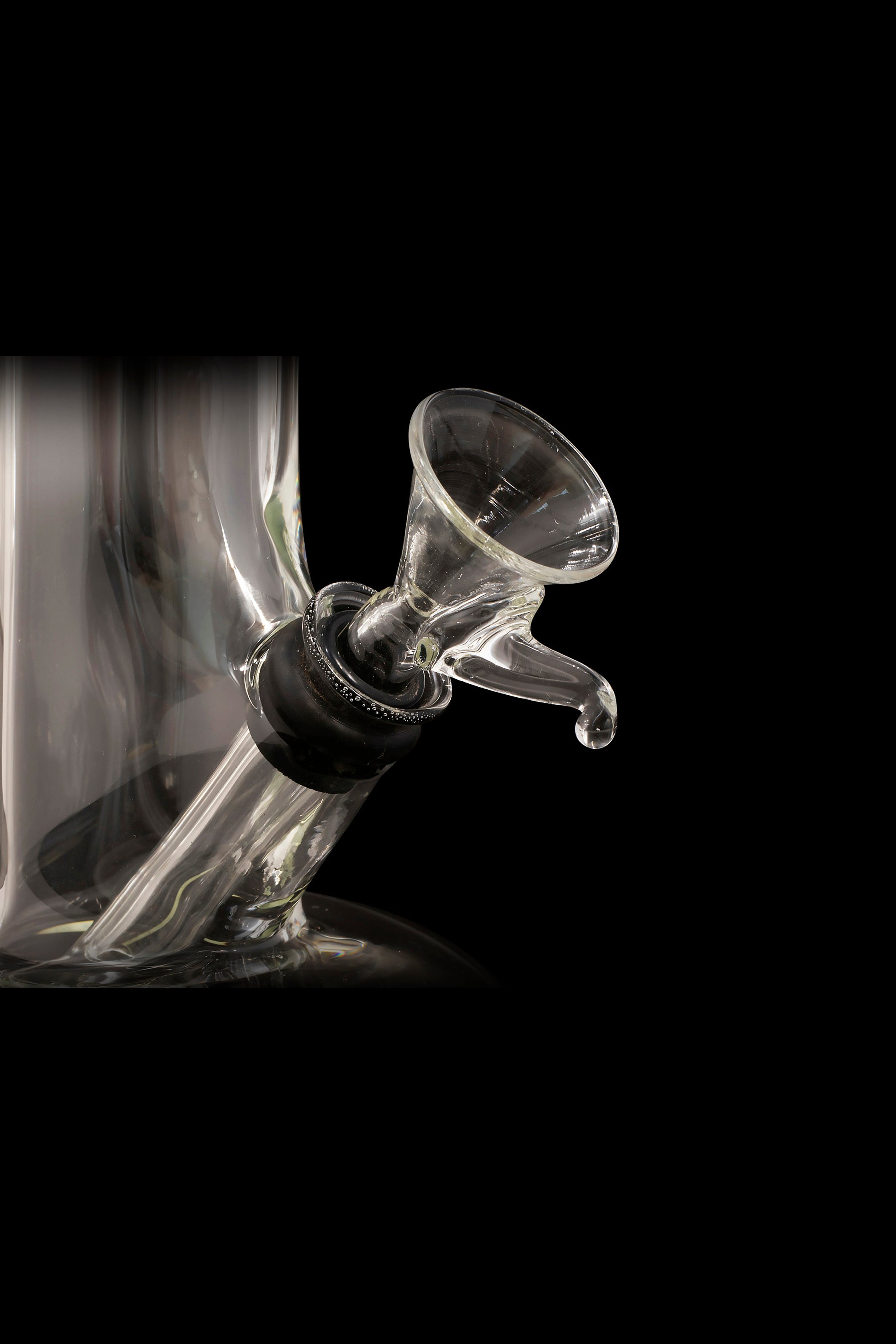 Glass cannabis oil rig with smoke against a black background.