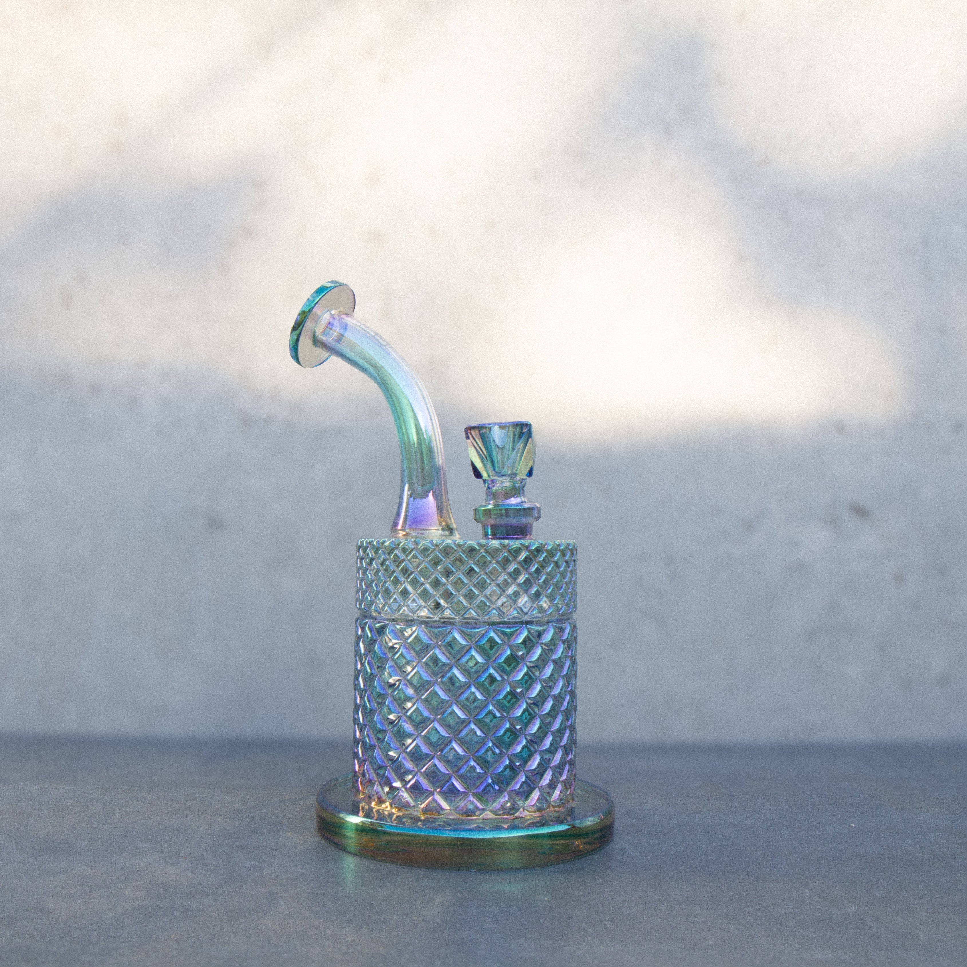 Iridescent glass rig with a bubbler attachment, used for vaporizing cannabis concentrates.