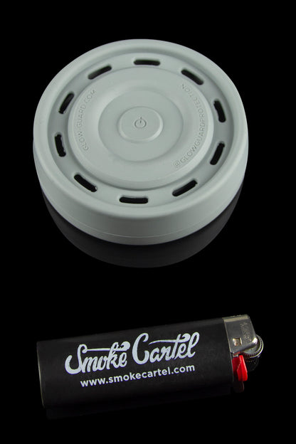 A grey silicone carb cap rests above a black lighter with "Smoke Cartel" branding and website address.