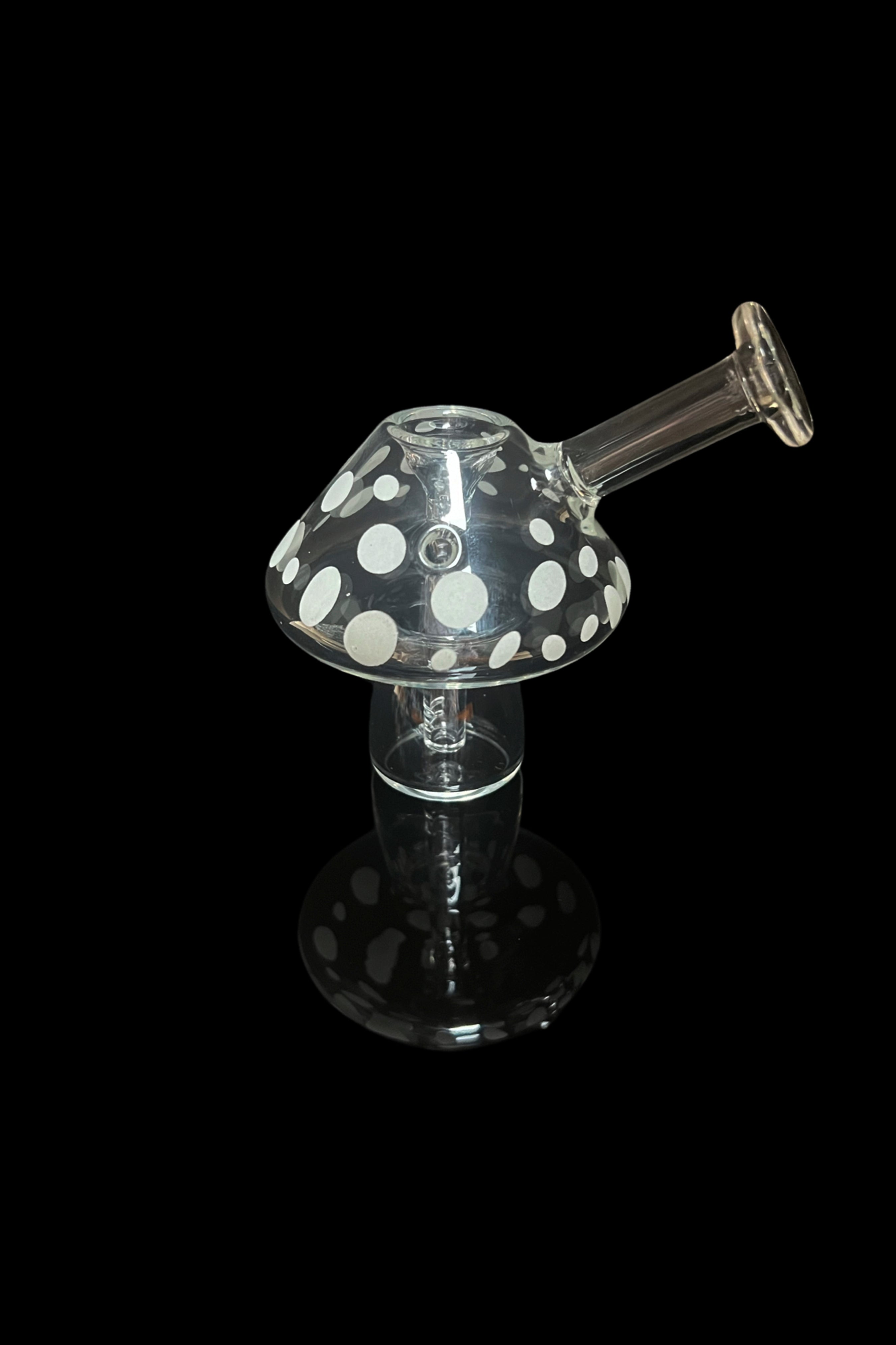Glass mushroom-shaped dab rig with white polka dots, isolated on black.