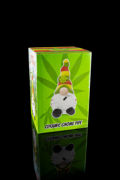 A vibrant green box displays a whimsical ceramic gnome pipe, reflected on a glossy surface, with cannabis leaf motifs.