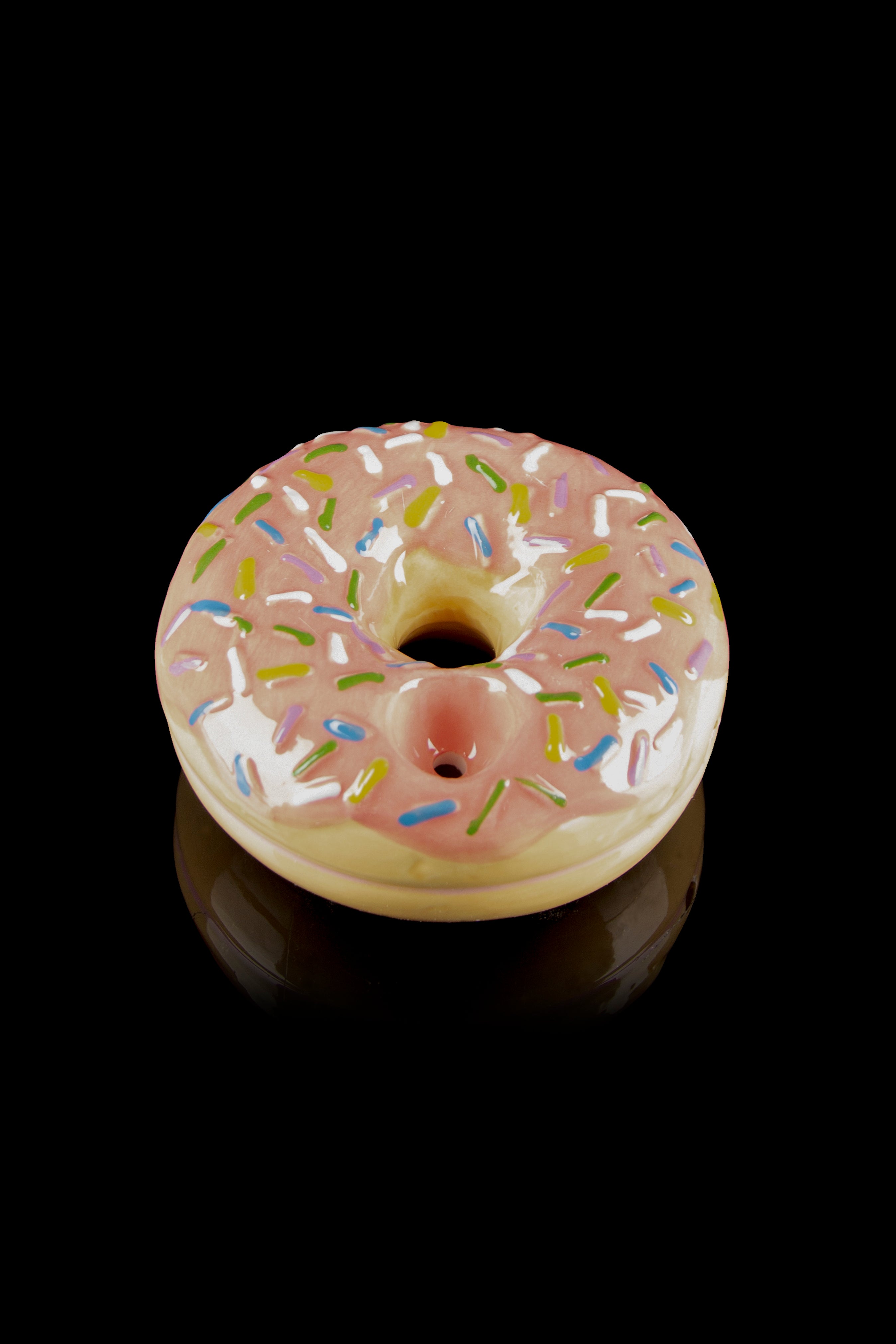 Pink glazed donut-shaped glass pipe with colorful sprinkles, studio shot on black.