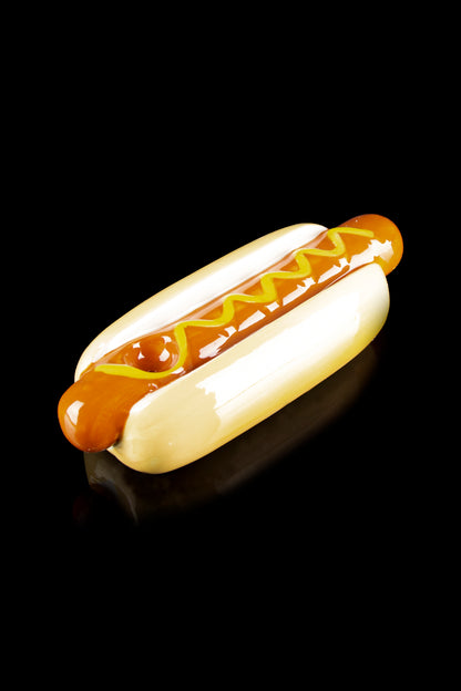 Hot dog-shaped silicone container with orange glaze-like accents, likely for cannabis concentrates.