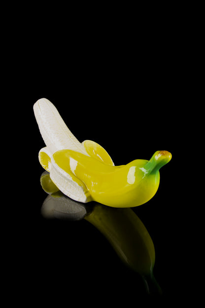 Green glass banana-shaped cannabis pipe with a reflective surface.