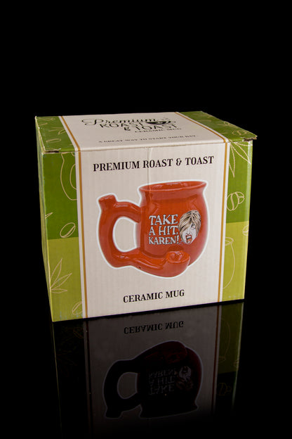 Product packaging for a novelty ceramic mug with a cannabis leaf design and the phrase "Take a hit, Karen!" reflecting on a glossy surface.