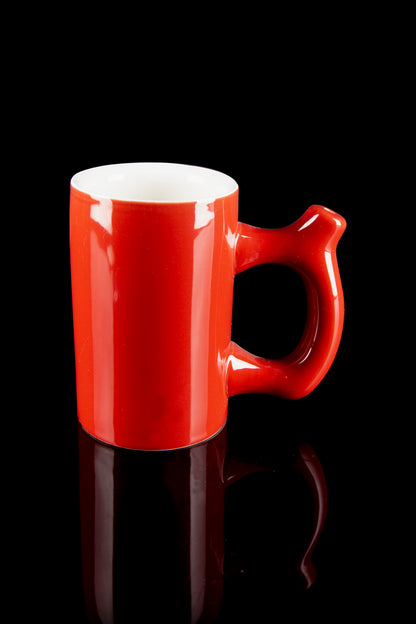 Red ceramic mug with a smooth, glossy finish, reflecting on a dark surface, likely for cannabis consumption.