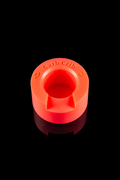 Red silicone carb cap with “Carb Crib” text, isolated on a black background.
