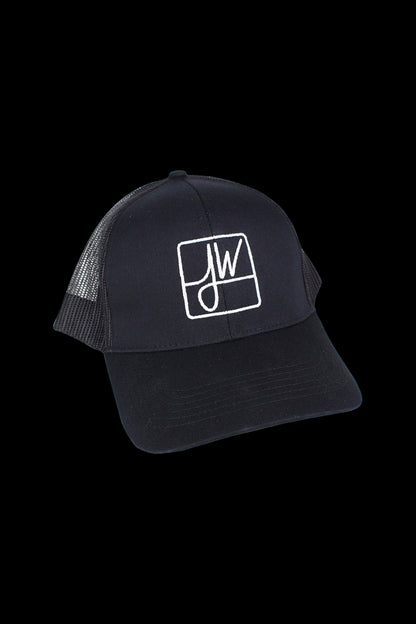 Angled close-up of a black Jane West Snapback Hat with a white embroidered "JW" square logo against a black background