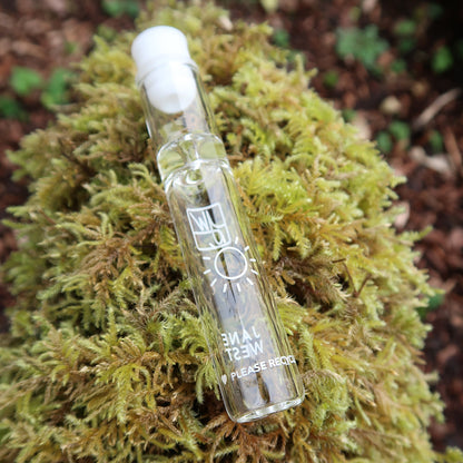 Glass cannabis oil applicator tube nestled in vibrant green moss.