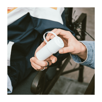 Hands holding a white cannabis container with a lanyard.