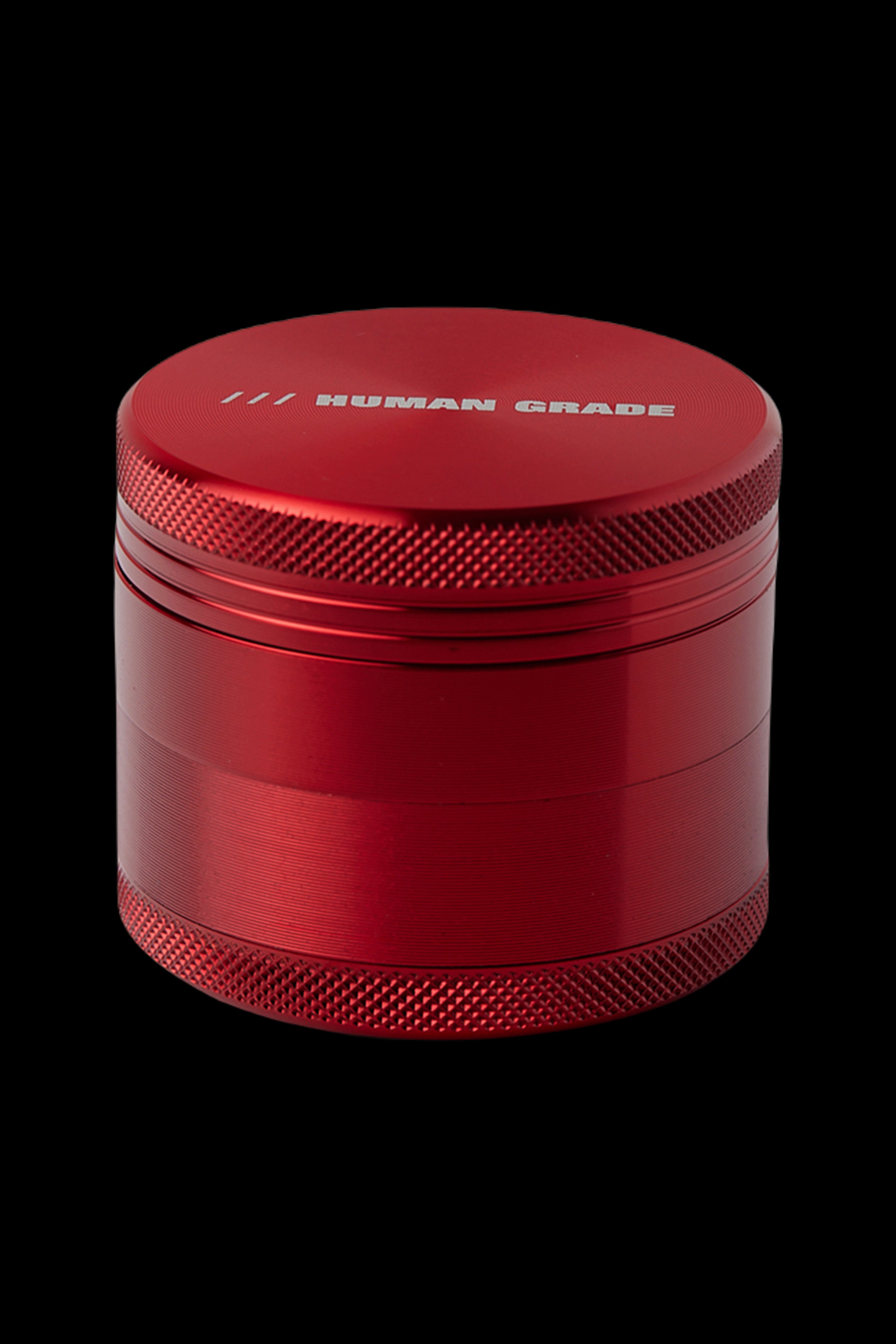 Red four-piece metal cannabis grinder with "HUMAN GRADE" etched on the lid.