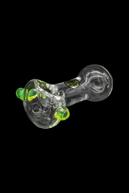 Green and clear glass cannabis pipe with swirling patterns, isolated on a black background.