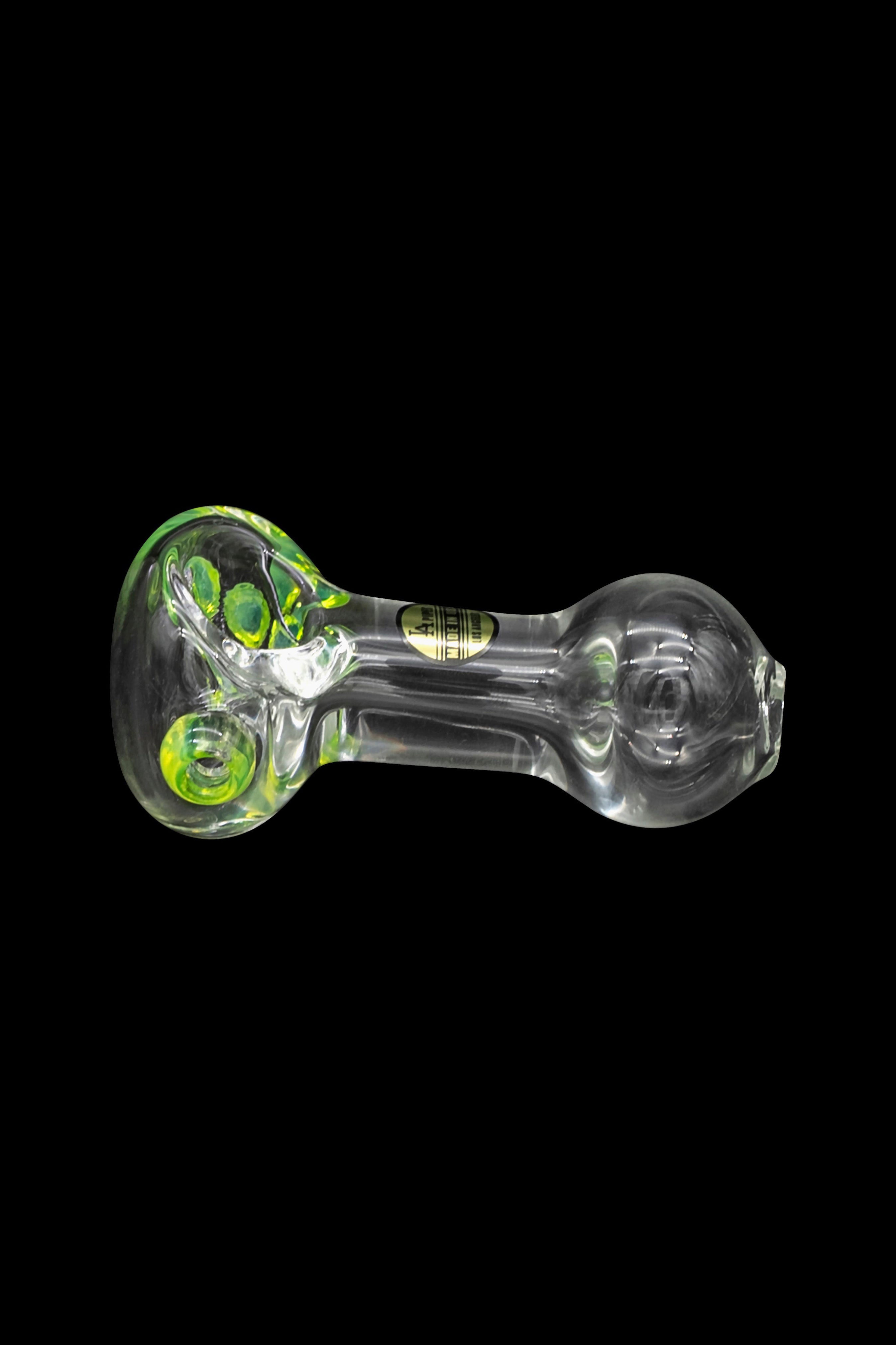 Glass pipe with green accents against a black background.
