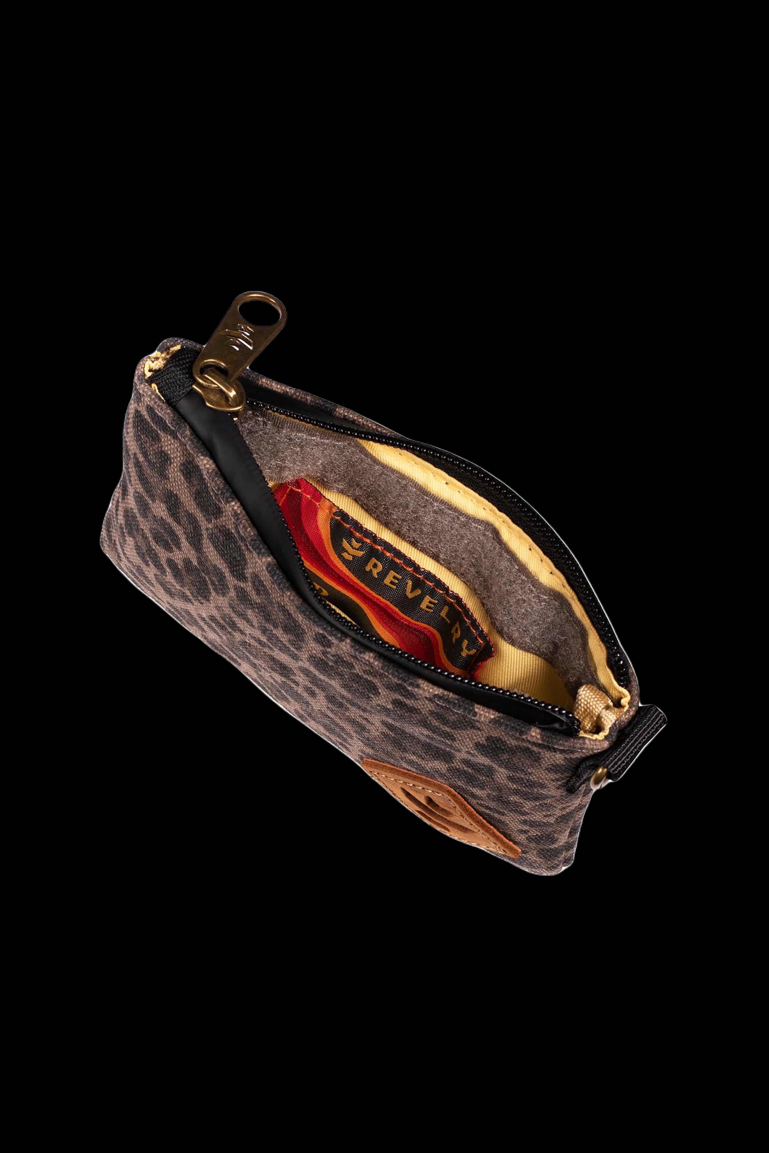 Angled close-up of the Revelry Supply Smell Proof Zippered Small Stash Bag - The Mini Broker showing a leopard‑print exterior, brass zipper pull, and yellow fabric interior.