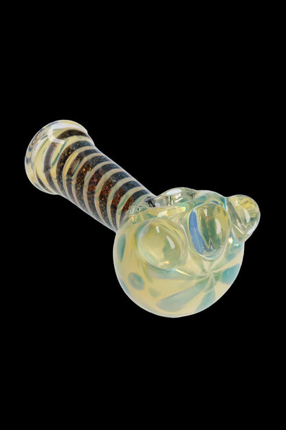 Glass pipe with striped handle and rounded bowl, isolated on a black background.