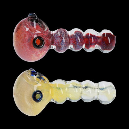 Two glass cannabis hand pipes with textured stems, one red and one yellow, isolated on a black background.