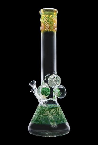 Straight-on view of the Smoke Cartel Mushroom Marble Water Pipe - 18 in. showing a clear beaker base with green swirl interior, three glass marbles on the neck, and a yellow-accented mouthpiece against a black background