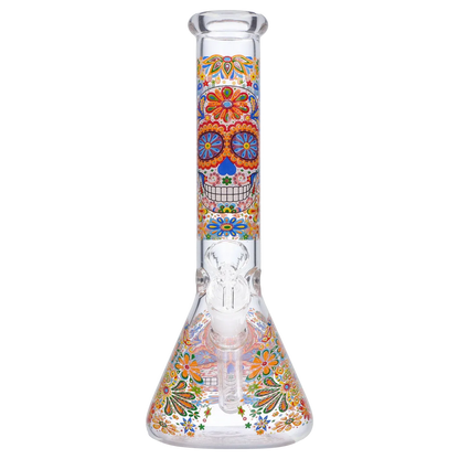 Front-facing close-up of the Smoke Cartel Skull Beaker Bong - 10 in. showing a colorful sugar-skull motif on the straight neck and floral-decorated beaker base.