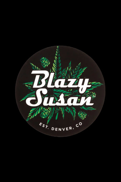 A circular sticker featuring the brand “Blazy Susan” in cursive white lettering surrounded by green cannabis leaves, with “EST. Denver, CO” at the bottom.