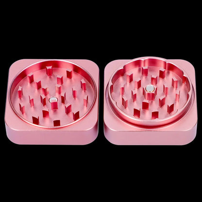 Pink metal cannabis grinder, disassembled into two halves showing the teeth for grinding.