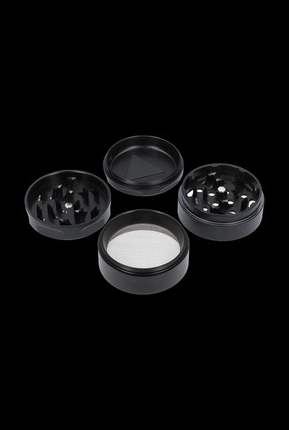 Black four-piece cannabis grinder with disassembled parts on a dark background.