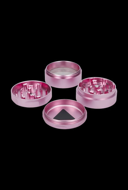 Pink four-piece cannabis grinder with visible grinding teeth and mesh filter.