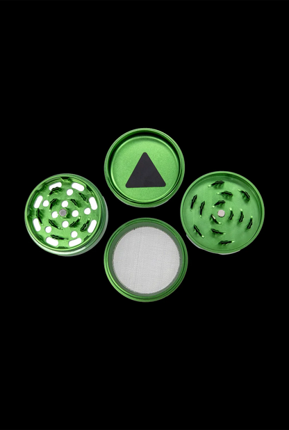 Disassembled green metal grinder with four parts—top, two grinding tiers, and collection chamber—isolated on a black background.