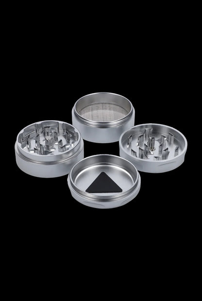 Silver cannabis grinder disassembled into four parts on a black background.