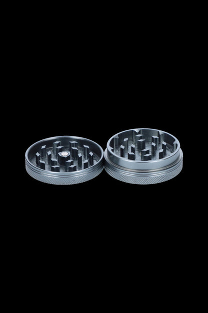 Silver cannabis grinder with two separated parts on a black background.