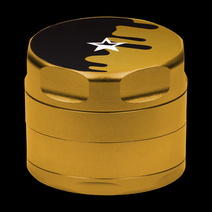 Close-up front view of the gold Famous Design-Surrender Aluminum 3 Stage Grinder-Gold showing its textured cylindrical body and black-topped lid with a white star.