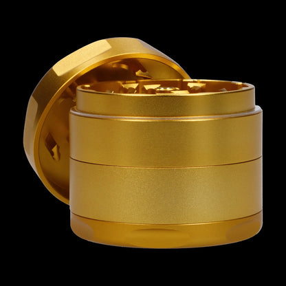 Close-up front angle of the Famous Design-Surrender Aluminum 3 Stage Grinder-Gold showing its metallic gold stacked chambers and exposed toothed interior against a black background