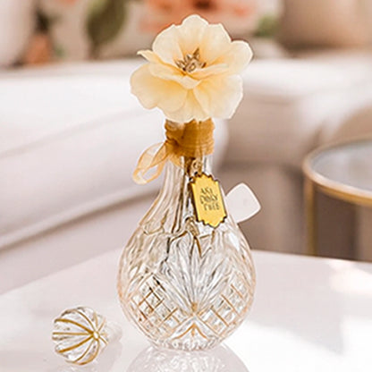 Close-up of a glass bud vase with a cream flower on top, the My Bud Vase "Stardust" Bong shown at three-quarter view on a white table.