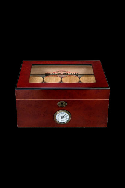 A polished wooden humidor with a glass top, displaying cannabis buds, and featuring a lock and humidity gauge.