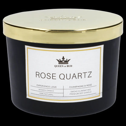 A white jar candle labeled “Rose Quartz” from “Queen of Bud” with gold trim, marketed as smoke eliminating and 100% natural.