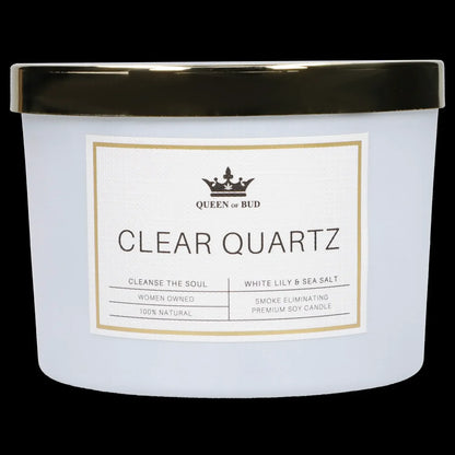 A white glass candle jar with a label reading "Queen of Bud Clear Quartz - Cleanse the Soul, White Lily & Sea Salt, Smoke Eliminating Premium Soy Candle."