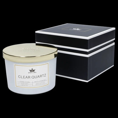 A glass jar candle labeled “Clear Quartz” by Queen of Bud, with scent notes of white lily & sea salt, presented in a black gift box.
