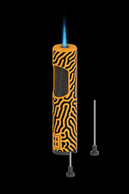 Orange and black patterned butane torch lighter with attached nozzle tips, isolated on a black background."