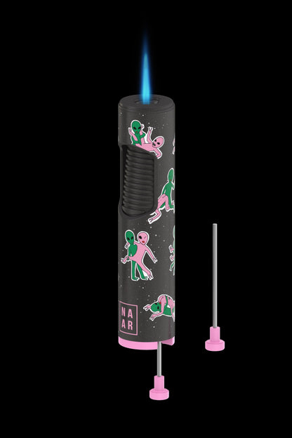Pink butane lighter with an alien-themed design, flames visible, accompanied by two pink dab tool attachments.