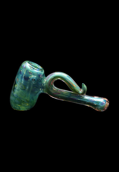 Side profile of the Smoke Cartel Gold Fume Bubble Trap Hammer Bubbler - 6 in., showing its iridescent green glass, bulbous bubbler chamber and curving hooked stem against a black background