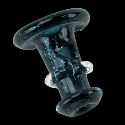 Diagonal close-up of the Nebula Black Empire Glassworks PuffCo 'New Peak' & Proxy Glass Joystick Cap showing glossy black glass flecked with tiny blue iridescent specks against a black background