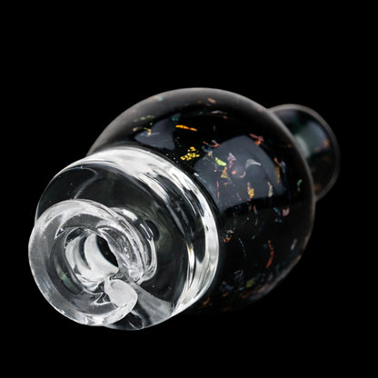 Angled close-up of the Empire Glassworks Puffco Pivot Glass Mouthpiece - Black Nebula showing its clear spiral tip and dark nebula-speckled glass body against a black background