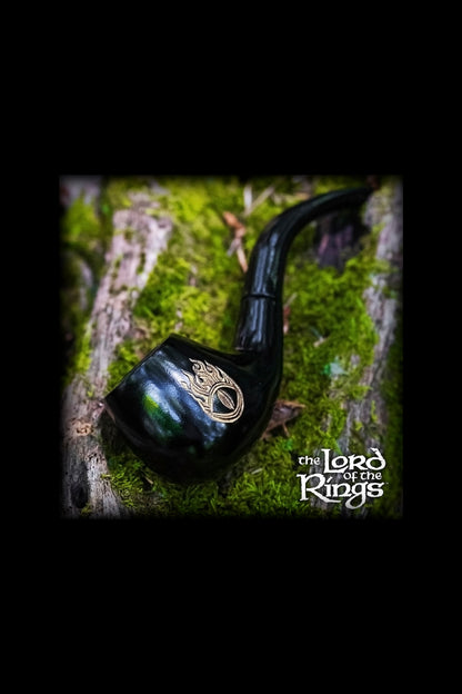 A green glass pipe with gold detailing rests against a mossy tree trunk, framed by a dark vignette and featuring ""The Lord of the Rings"" logo."