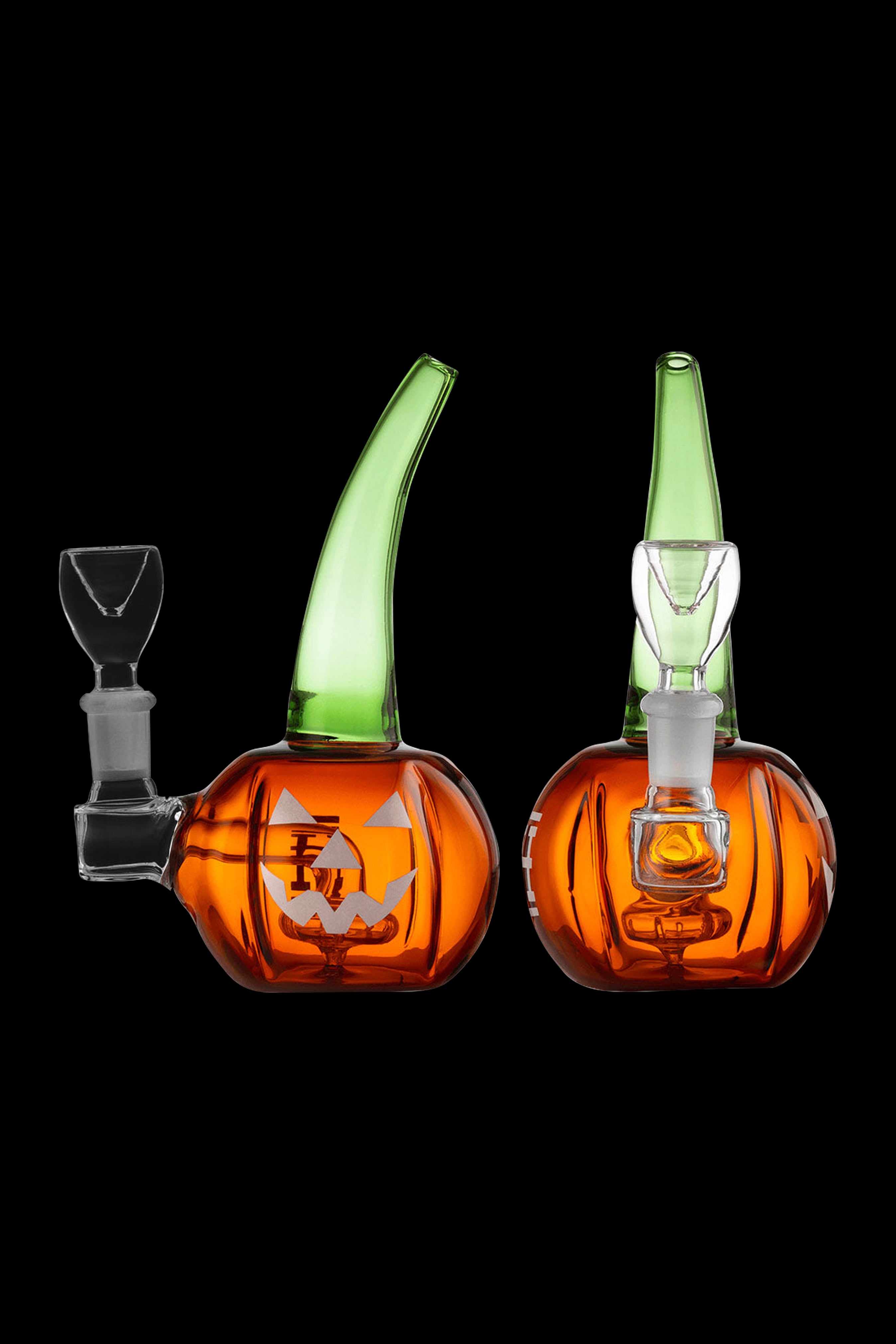 Two orange and green glass pumpkin-shaped dab rigs with clear glass attachments, isolated on a black background.