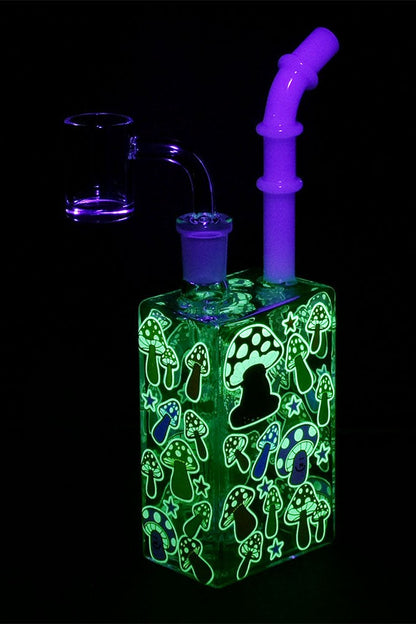 Glowing green glass bubbler with a whimsical mushroom and star pattern, illuminated under blacklight.
