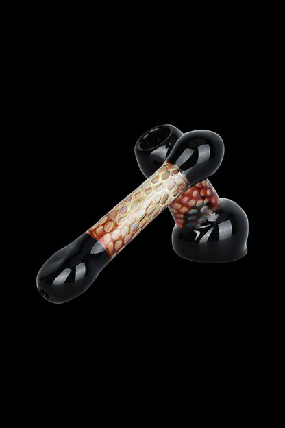 Glass cannabis pipe with intricate red and beige patterned center section, isolated on a black background.