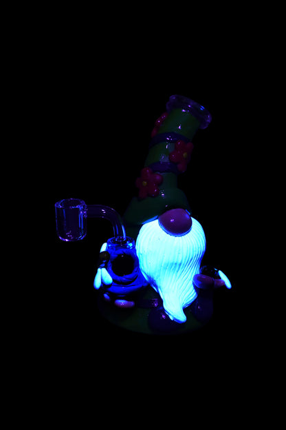 Glow-in-the-dark glass dab rig with a spherical chamber and intricate design, isolated on black.